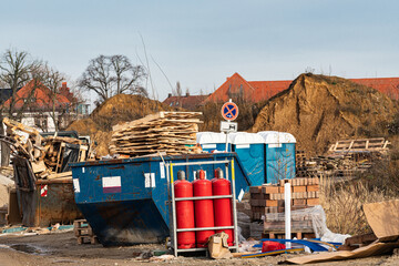 Dump site with waste containers, building materials and gas cylinder