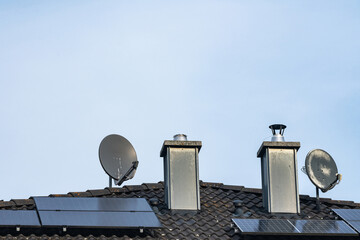 Solar panels and satellite dishes on a building roof at daytime