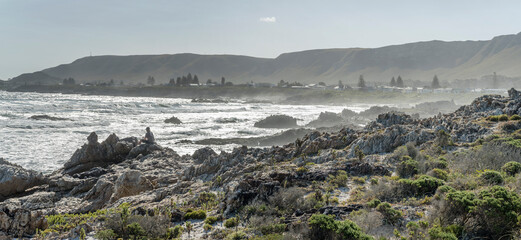 fishing in backlight on cliffs shore at Kammabaai Beach cove, Hermanus, South Africa