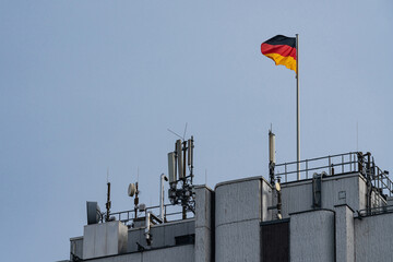 Flag of Germany on top of a building with antennas and blue sky