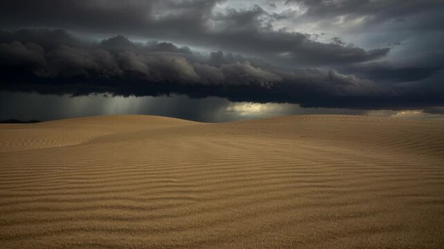 Dark storm clouds rolling over rippled desert sand dunes under dramatic sky with distant rainfall on remote barren landscape