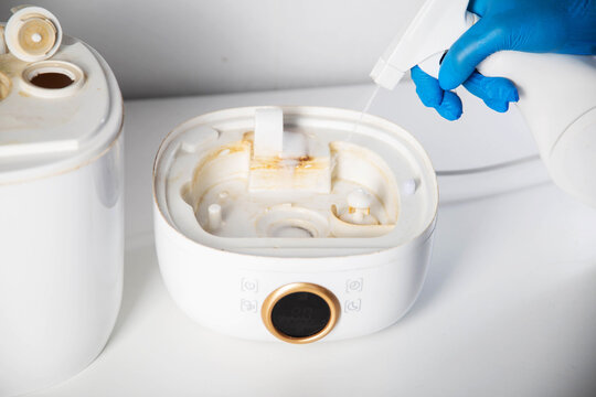 Spraying a chemical rust and scale remover into a humidifier. Home humidifier maintenance, close-up