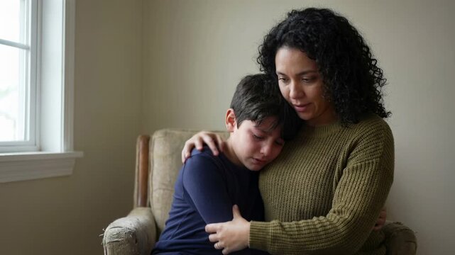 Comforting mother embracing upset child in cozy living room, offering emotional support and reassurance during a moment of sadness