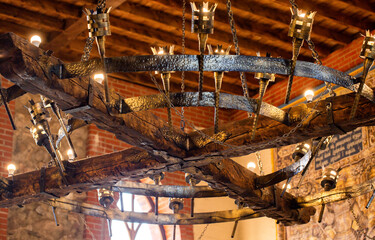 A beautiful antique wrought iron chandelier with chains hangs from the ceiling. Retro style,...