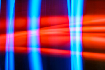 Abstract image features a blurred light painting technique, showcasing vibrant hues of red and blue in geometric shapes. The dynamic composition creates a sense of movement and energy