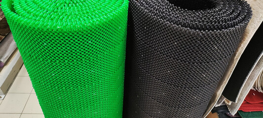 Rolled-up plastic mats vibrant green dark grey textured surface display retail store flooring solution anti-slip material home improvement product shower mat bath mat entryway mat