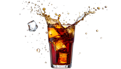 A glass of dark soda with ice cubes, exploding with liquid droplets