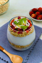 Deliciously layered parfait featuring creamy yogurt, crunchy oats, vibrant strawberries, and fresh kiwi slices meticulously arranged for a healthy breakfast delight.