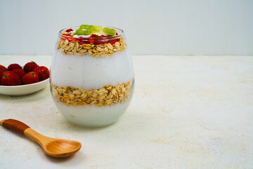 A refreshing layered parfait featuring creamy yogurt, crunchy oats, vibrant strawberries, and bright kiwi slices, perfect for a healthy breakfast or nutritious snack item.