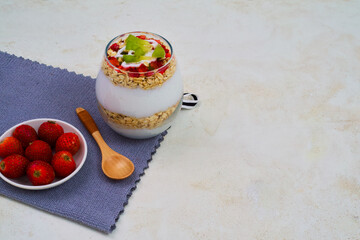 Delicious layered yogurt parfait featuring creamy white yogurt, crunchy granola oats, fresh strawberries, and bright green kiwi slices served ready to eat.