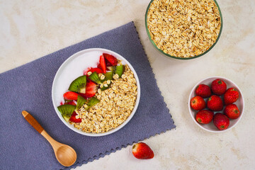 Delicious and healthy bowl of overnight oats topped with vibrant sliced kiwi and fresh strawberries, ready for a nutritious morning meal.