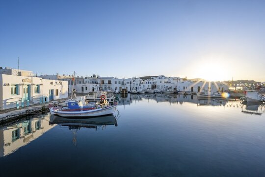 Fishing boats in the harbour of Naoussa at sunset, reflected in the sea, Sun star, White Cycladic houses, Naoussa, Paros, Cyclades, Greece