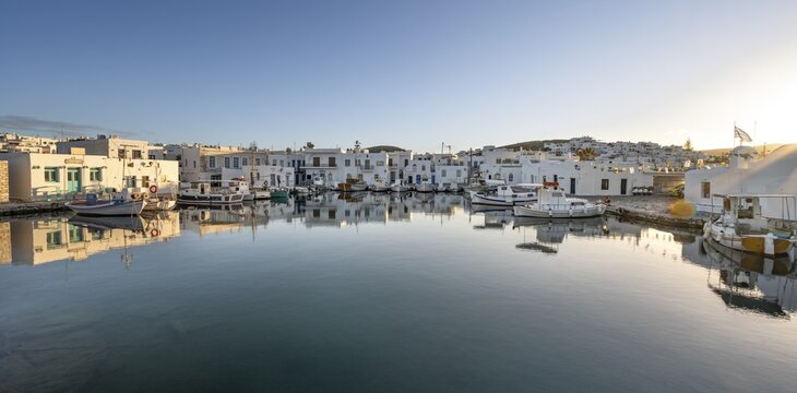 Fishing boats in the harbour of Naoussa at sunset, reflected in the sea, White Cycladic houses, Naoussa, Paros, Cyclades, Greece