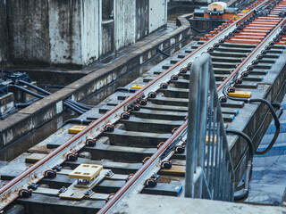 Close-up of modern railway track infrastructure with steel rails, sleepers, sensors, and cabling in an urban transit system, highlighting precision engineering, maintenance, and transportation.