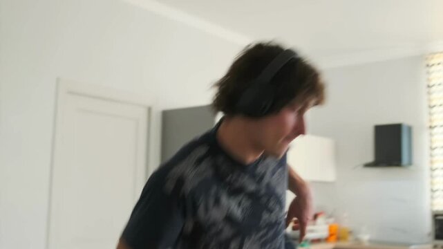 A curly-haired funky man in a black T-shirt and headphones dances ener