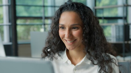 Positive Hispanic business woman talking video call in office smiling cheerful businesswoman female girl talk conference computer virtual chat interview job work discuss consulting client negotiating