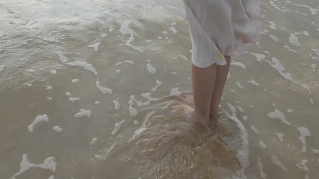 Serene woman enjoys peaceful moment at beach with waves washing over her feet