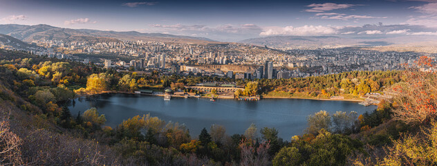 Turtle Lake in autumn, surrounded by colorful foliage, with the expansive cityscape of Tbilisi,...