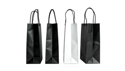 Four paper shopping bags, three black, one white, with black handles, against a black backdrop