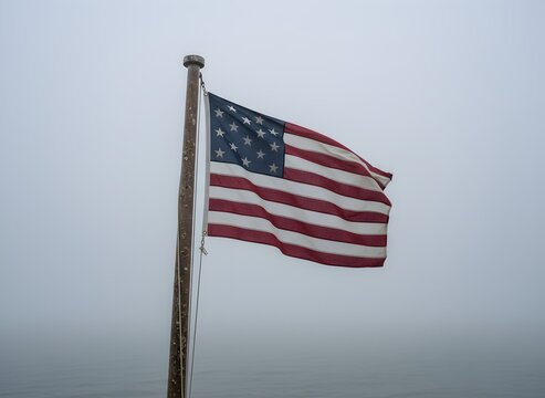 The Serapis Flag Waving on Weathered Wooden Pole Against Foggy Sky, Representing American Heritage and Independence