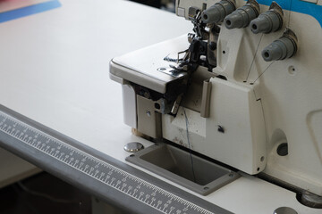 Industrial sewing machine with black thread, positioned on a clean workspace, showcasing precision stitching and craftsmanship in textile production and design process