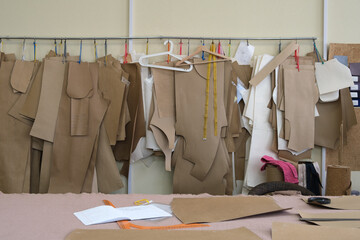 Collection of various fabric patterns and templates hanging on a rack in a sewing workshop, showcasing the art of garment design and tailoring techniques