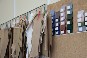 Collection of fabric patterns and color swatches hanging on a wall in a design studio, showcasing various textures and materials for fashion design projects