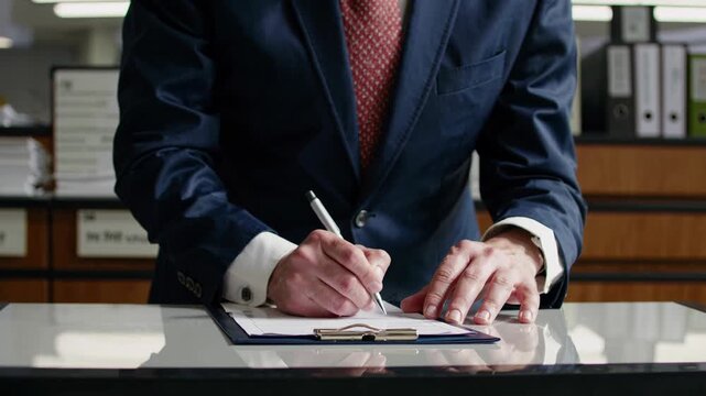Suited executive signing contract on desk with firm pen, corporate manager completing agreement, rows of binders in background, steady hands and formal cufflinks convey authority