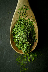 Dried wild garlic leaves on a wooden spoon. Top view