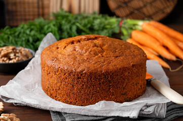 Carrot cake with cinnamon, walnuts and cream cheese frosting on a plate on a dark wooden background. Rustic style. Copy space.