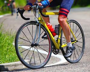 legs cyclist pedaling energetically on yellow racing bicycle during race