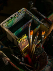Collection of Used Artist Paintbrushes in Container with Paint Palette