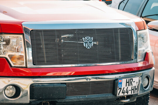 6 November 2025, Batumi, Georgia: Red pickup truck displaying a custom autobot transformer robotic symbol emblem on its chrome front grille
