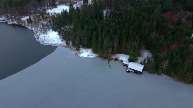 Aerial drone shot of Barmsee lake in southern Germany. Winter scenery with partial ice cover, snow and mountain landscape of the Karwendel region. Cinematic drone footage of Barmsee in Oberbayern