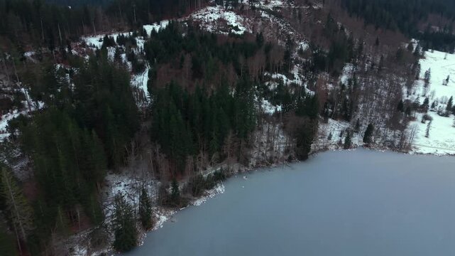 Scenic travel video. Aerial view of a frozen lake in Bavaria. Cinematic drone footage of frozen Barmsee and Karwendel mountains. Luftaufnahme des Barmsees im Winter. Wanderweg am Barmsee im Schnee.
