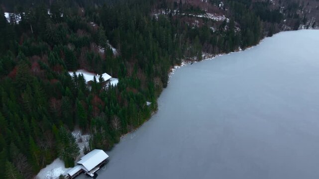 Winterlicher Drohnenflug zeigt gefrorenen Bergsee, umliegende Waelder und Karwendel Gebirge. Cinematic drone footage of Barmsee in Oberbayern, Germany. Winter aerial view highlights frozen lake