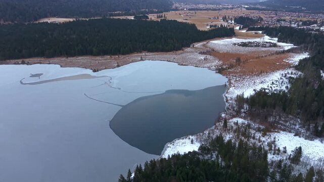 Drohnenvideo ueber den Barmsee im Landkreis Garmisch-Partenkirchen. Winterliche Luftansicht eines gefrorenen Sees mit Wald und alpiner Berglandschaft. Drone shot over Lake Barmsee southern Germany