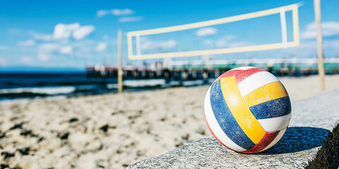 Volleyball resting on a concrete ledge with a beach court, net, and ocean view on a sunny day