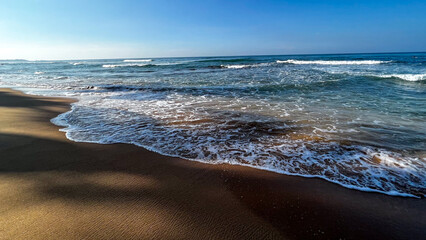 Tranquil azure waves kiss sunlit sands, evoking serene mindfulness amidst Ocean Day reflections and coastal renewal celebrations