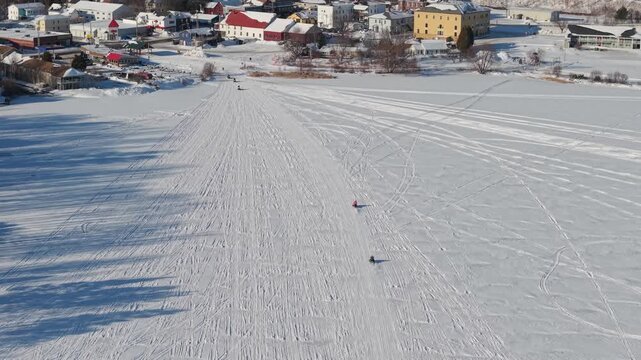 Snowmobiles on frozen lake with the village of Island Pond Vermont 
