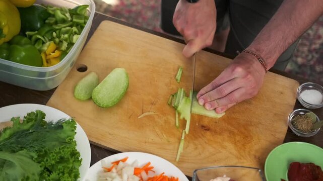 Male hands make precise slices of green daikon on a wooden cutting boa
