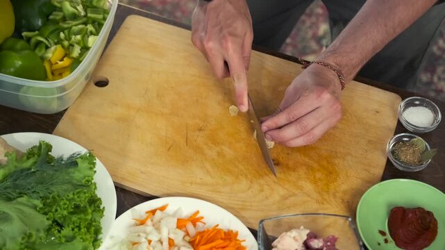 Male hands slice ginger into thin pieces on a wooden cutting board whi