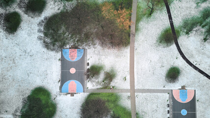 Drone view of outdoor basketball court and park covered in snow