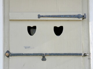 Light gray wooden shutter with heart cutouts and decorative fittings. Traditional and historic. Copyspace.