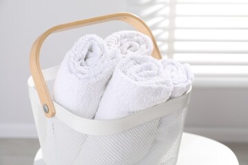 Laundry basket with towels on white table indoors, closeup