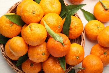 Fresh tangerines and green leaves on light table, above view