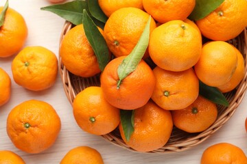 Fresh tangerines and green leaves on white wooden table, flat lay