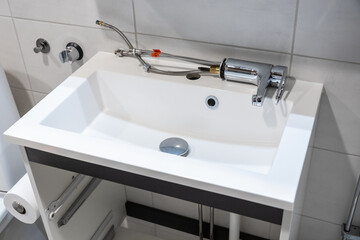 Fototapeta premium Bathroom sink during faucet replacement with tools around. Home renovation scene showing plumbing repair, maintenance, and installation work in progress