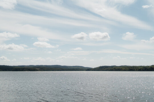 Wide panoramic view of Stora Hornsj&ouml;n lake with distant forested horizon and wispy clouds, Sweden