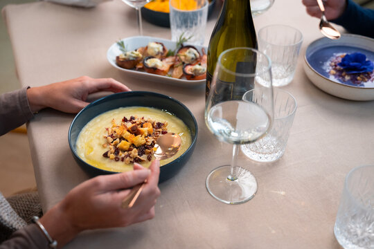Close-up of creamy gourmet soup served at an elegant home dinner with white wine and refined table setting